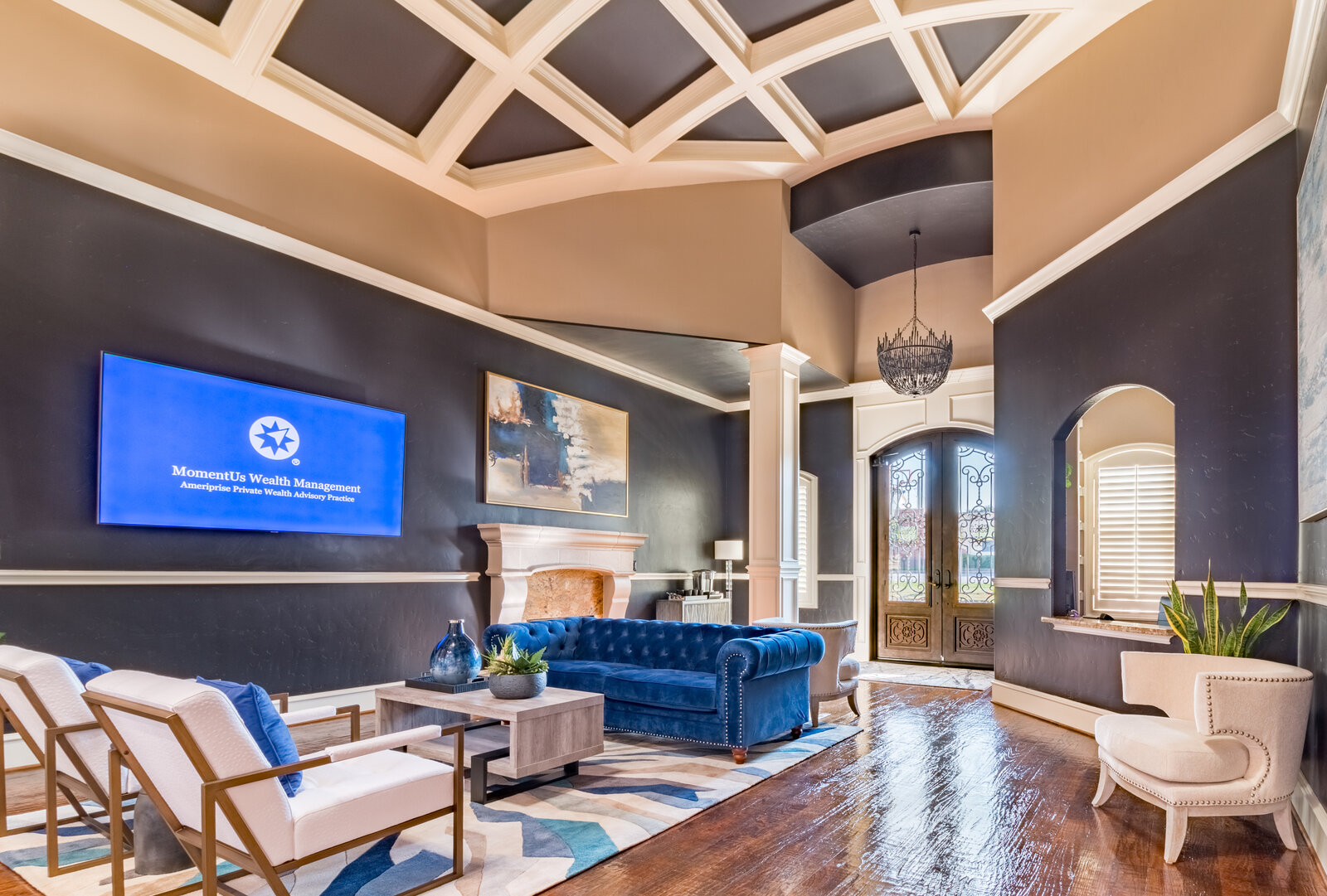 Reception lounge designed by Landry Designs with navy walls and tufted velvet sofa at the MomentUs Wealth Management office